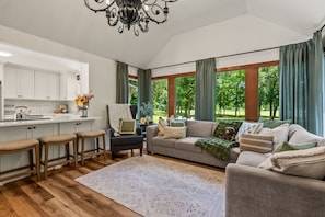 A modern living room with a sofa, a coffee table, and a dining area with a kitchen counter.