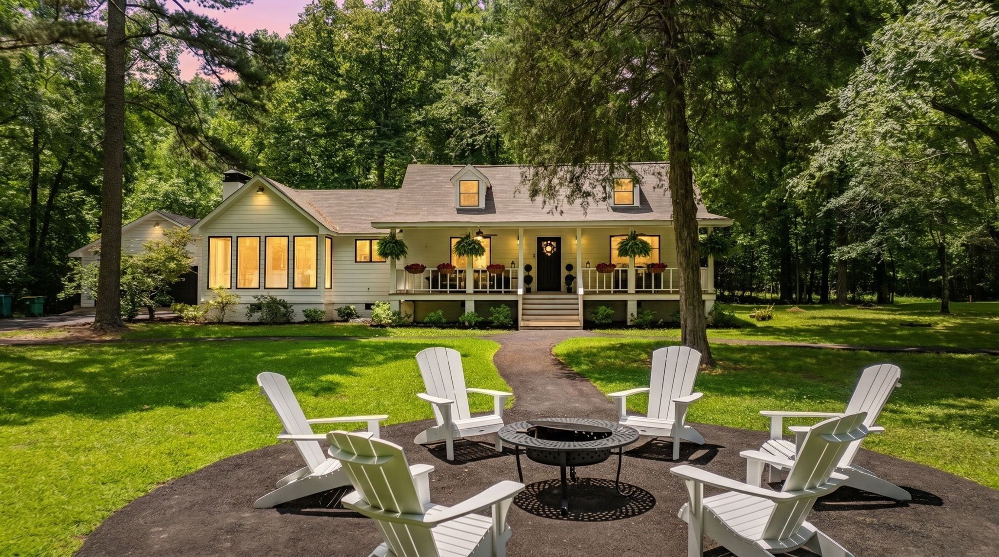 A house with a porch, a fire pit, and four Adirondack chairs.