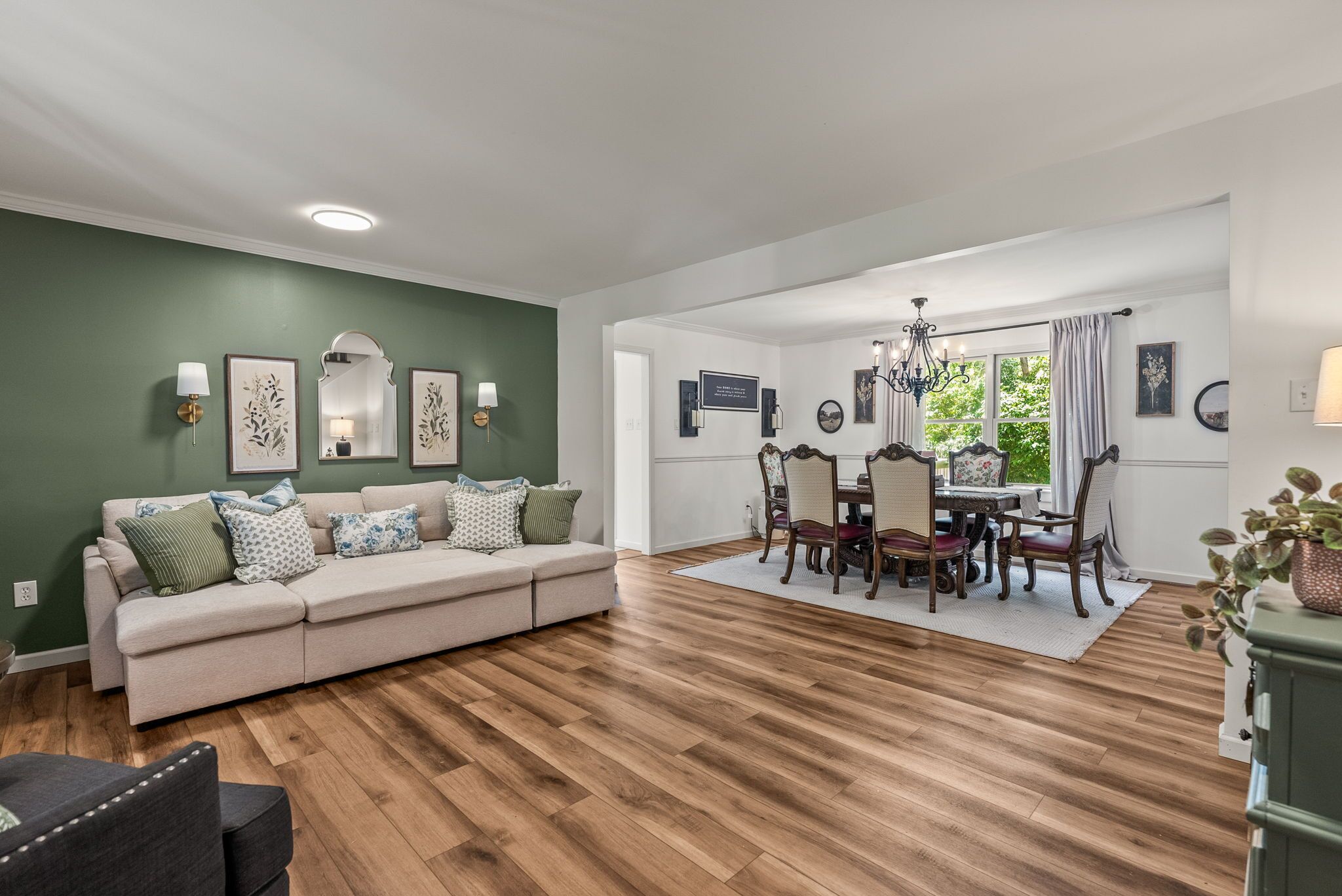 Un salón amplio con un sofá color crema, suelo de madera y un comedor con mesa y sillas.