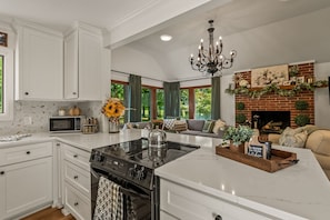 A kitchen with a central island, white cabinetry, a built-in oven, and a microwave.