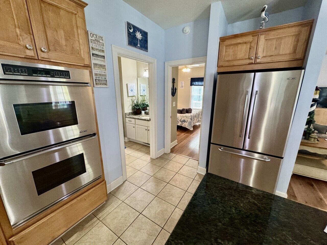 A kitchen with stainless steel appliances, wooden cabinets, and a tiled floor.