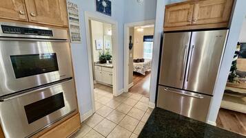 A kitchen with stainless steel appliances, wooden cabinets, and a tiled floor.