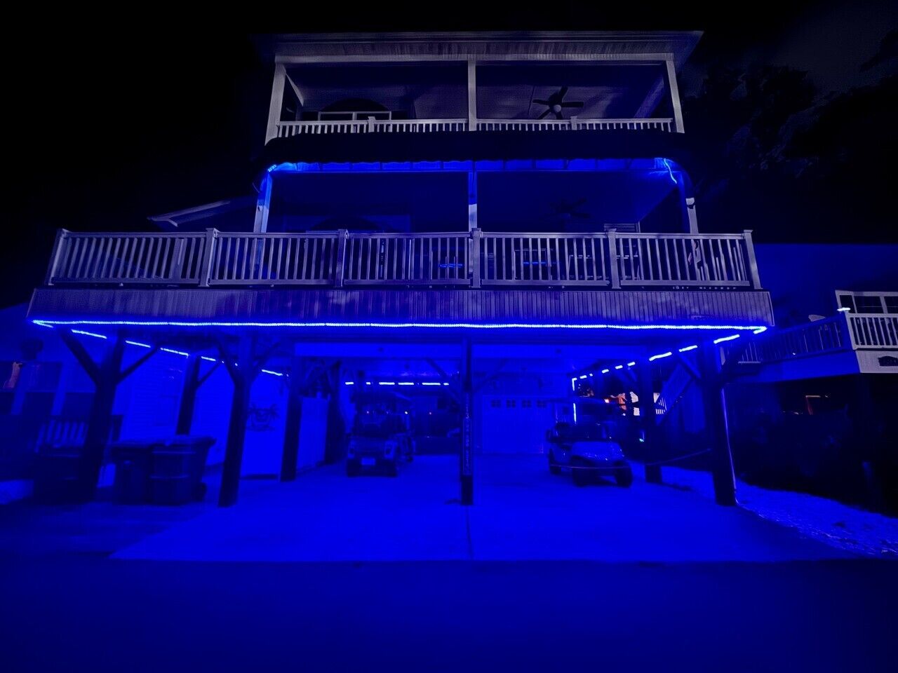 A two-story building with a covered parking area and a balcony on the upper floor.