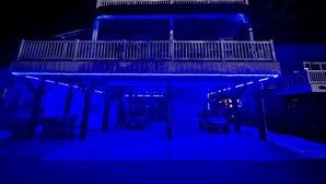 A two-story building with a covered parking area and a balcony on the upper floor. - Ocean Lakes Beach House-Golf Cart Included-Fire Pit-King Suite-Linens (Myrtle Beach)