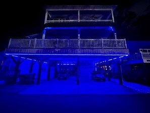 A two-story building with a covered parking area and a balcony on the upper floor. - Ocean Lakes Beach House-Golf Cart Included-Fire Pit-King Suite-Linens (Myrtle Beach)