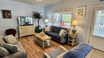 A living room with a sofa, armchair, coffee table, and a television.