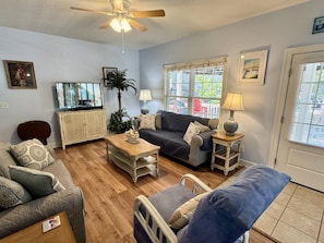 A living room with a sofa, armchair, coffee table, and a television. - The Salty Rooster | Ocean Lakes 4BR | Golf Cart + Fire Pit | Sleeps 8 (Myrtle Beach)