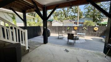 A covered patio area with a concrete floor, wooden deck, and a white railing.