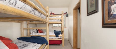 Habitación con literas, ventana, puerta y un cuadro en la pared.