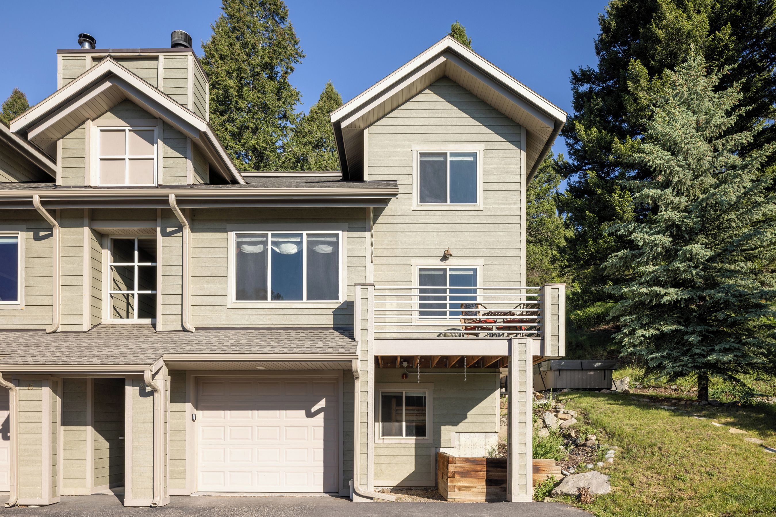 A two-story house with a garage, a covered porch, and a small deck.