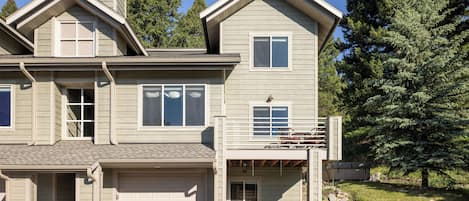 A two-story house with a garage, a covered porch, and a small deck.