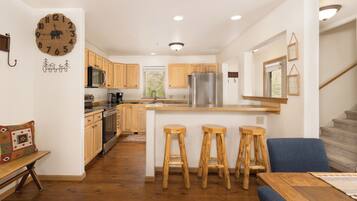 A modern kitchen with wooden cabinets, a stainless steel refrigerator, and a central island with bar stools.