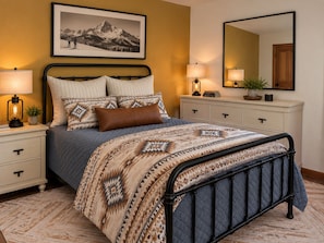 A bedroom with a bed, bedside tables, a dresser, a mirror, and a framed picture on the wall. - The Bears Den - 4-BR chalet in Big Sky for your getaway - Private Hot Tub! (Big Sky)