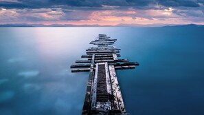 A wooden pier extending into calm water with mountains in the background. - VN Turiassu (São Paulo)