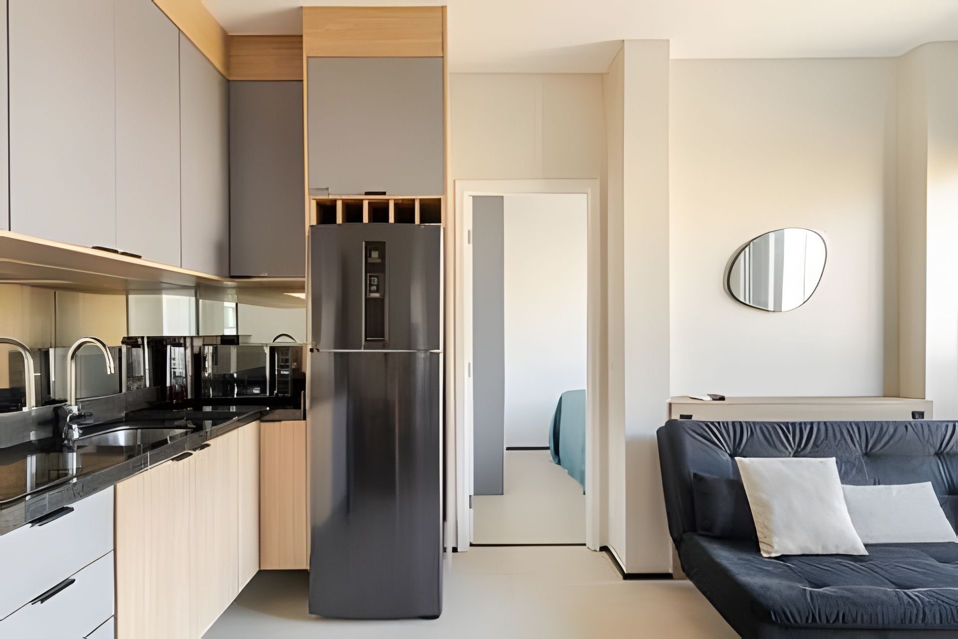 A modern kitchen with a built-in refrigerator, a dining area with a sofa, and a mirror on the wall.