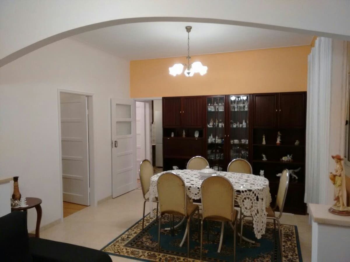 A dining area with a table and chairs, a chandelier, and a cabinet with glass doors.
