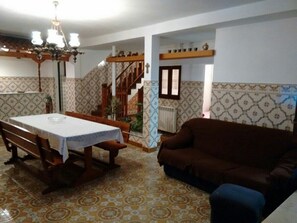 A dining area with a table and benches, a brown sofa, and a staircase leading to an upper level.