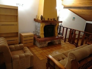 A living room with a fireplace, wooden furniture, and a staircase.