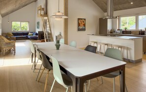 A spacious dining area with a long table and chairs, a kitchen with a bar, and a loft bedroom with a wooden ceiling. - Nice home in Ebeltoft with WiFi (Ebeltoft)