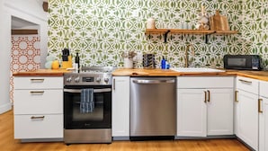 Una cocina con armarios blancos, electrodomésticos de acero inoxidable, encimera de madera y salpicadero decorativo.