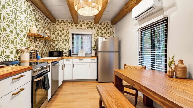 Una cocina con armarios de madera, un refrigerador de acero inoxidable, una mesa de madera y un banco.