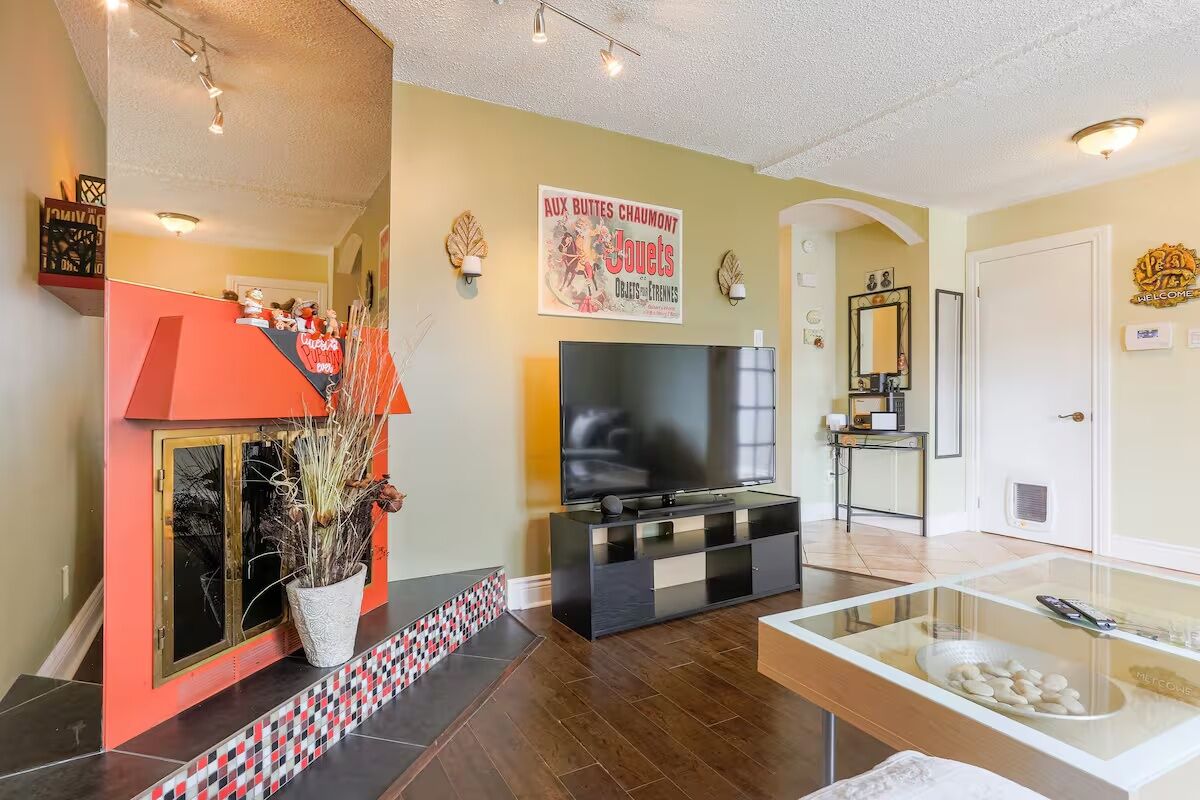A living room with a television, a red cabinet, a decorative plant, and a glass display case.