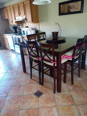 A kitchen with wooden cabinets, a dining table with chairs, and a tiled floor. - Cozy 2 bedroom close to downtown, public transportation & airport (Montréal)