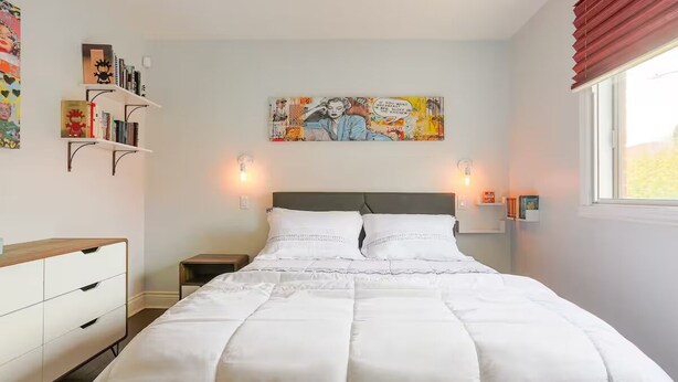 A bedroom with a large bed, bedside tables, a dresser, a wall-mounted shelf with books, and a painting. - Cozy 2 bedroom close to downtown, public transportation & airport (Montréal)