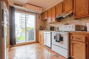 A kitchen with wooden cabinets, a stove, and a dishwasher. - Cozy 2 bedroom close to downtown, public transportation & airport (Montréal)