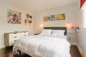 Ein Schlafzimmer mit einem Bett, einem Nachttisch, einer Kommode und zwei Wandleuchten.