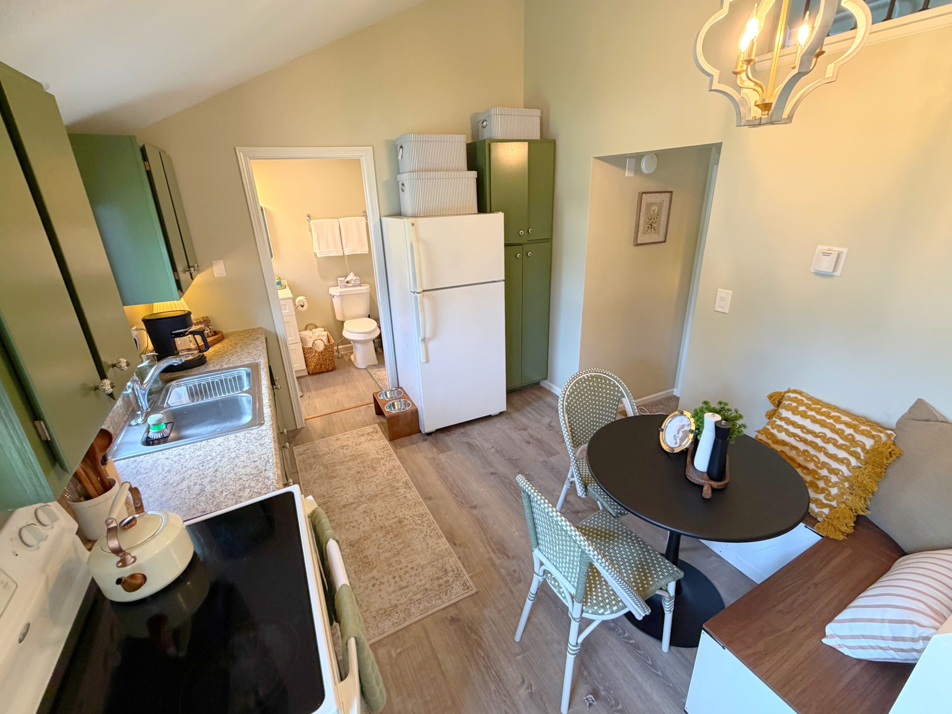 Een kleine keuken met een koelkast, gootsteen en een eethoek met tafel en stoelen.