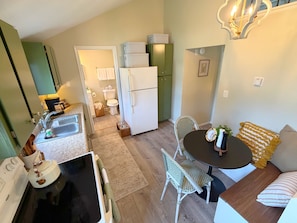 A compact kitchen with a refrigerator, sink, and a dining area with a table and chairs.