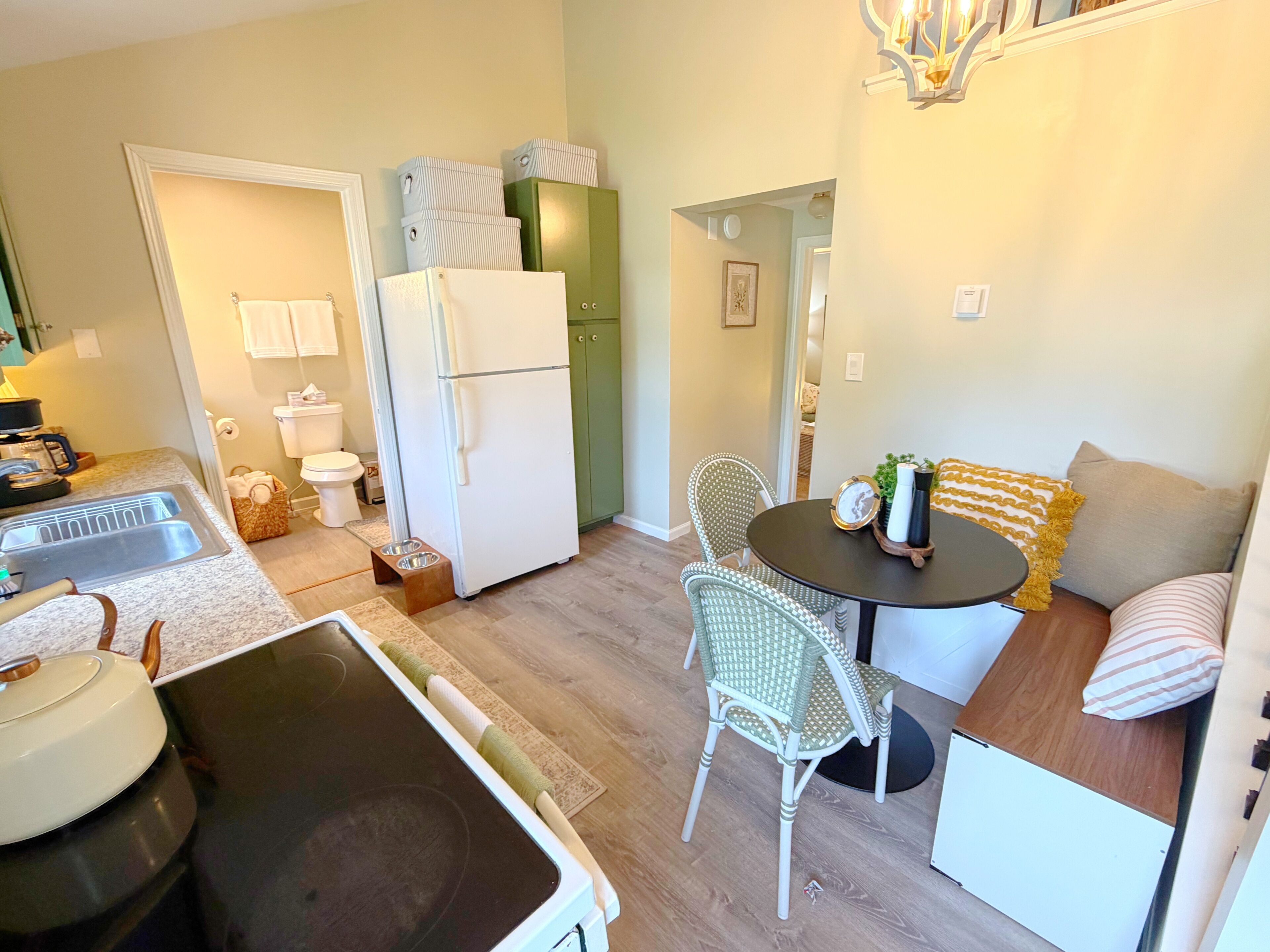 A compact kitchen with a refrigerator, sink, and dining area with chairs and a table.