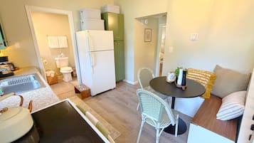 A compact kitchen with a refrigerator, sink, and dining area with chairs and a table.
