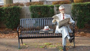A bench with a plaque, a hat, and a newspaper. - cozy elegant efficiency (Harrisburg)
