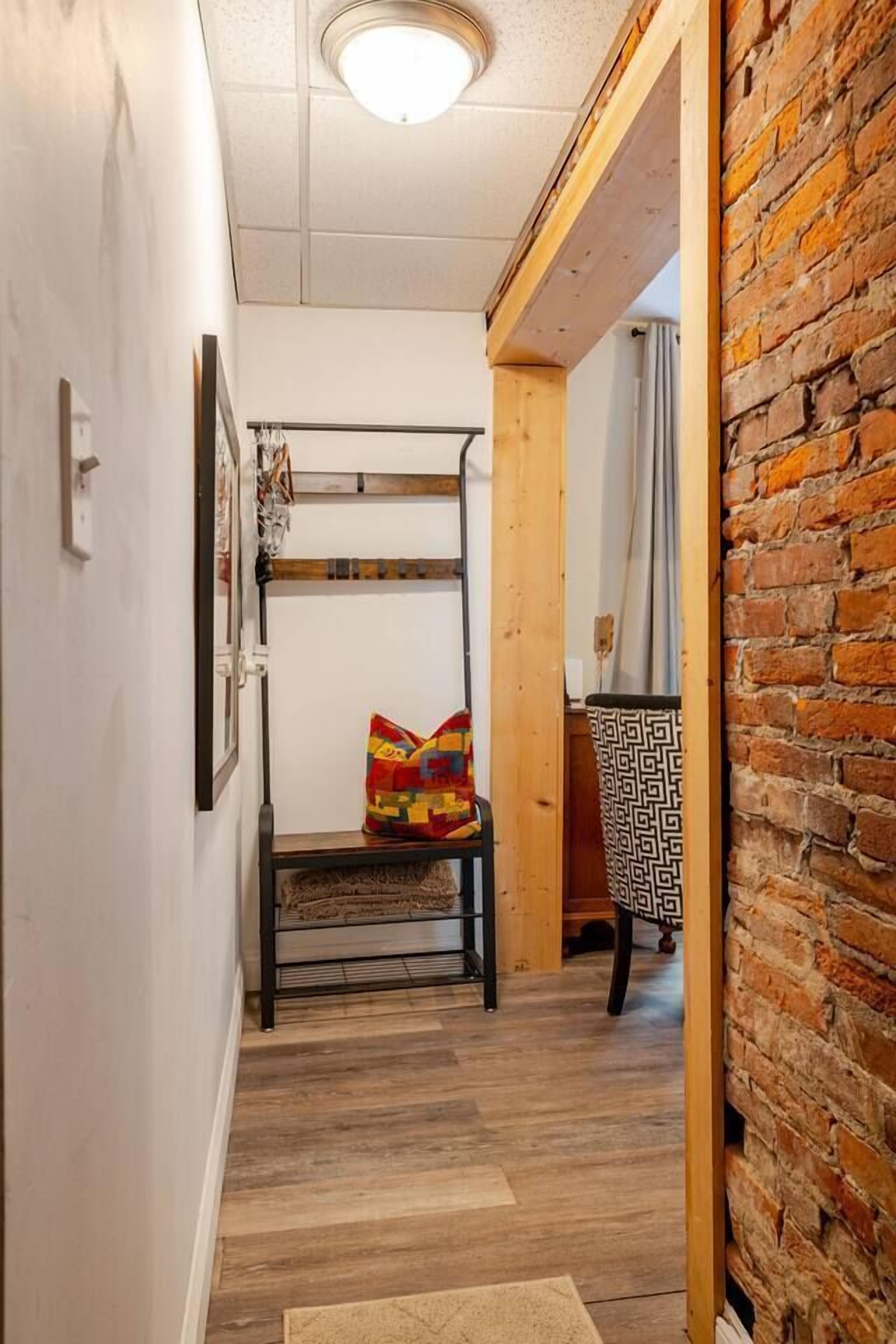 A narrow hallway with a bunk bed, a chair, and a patterned wall.