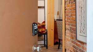 A doorway leading to a room with a brick wall and a framed artwork. - cozy elegant efficiency (Harrisburg)