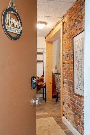 Una puerta que da a una habitación con pared de ladrillo y una obra de arte enmarcada.