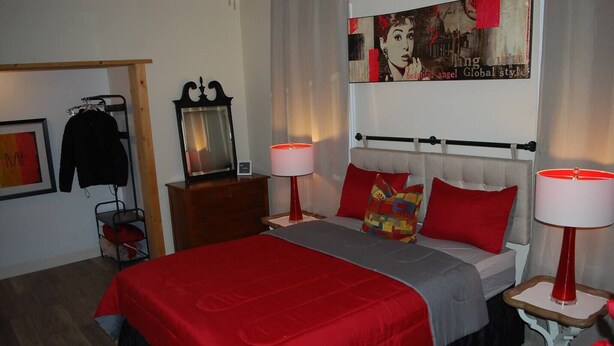 A hotel room with a bed, two bedside lamps, a dresser, a mirror, and a poster on the wall. - cozy elegant efficiency (Harrisburg)