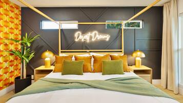 A modern bedroom with a bed, two bedside tables, a neon sign, and a potted plant.