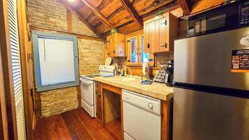 A compact kitchen with a refrigerator, stove, sink, and wooden cabinets.