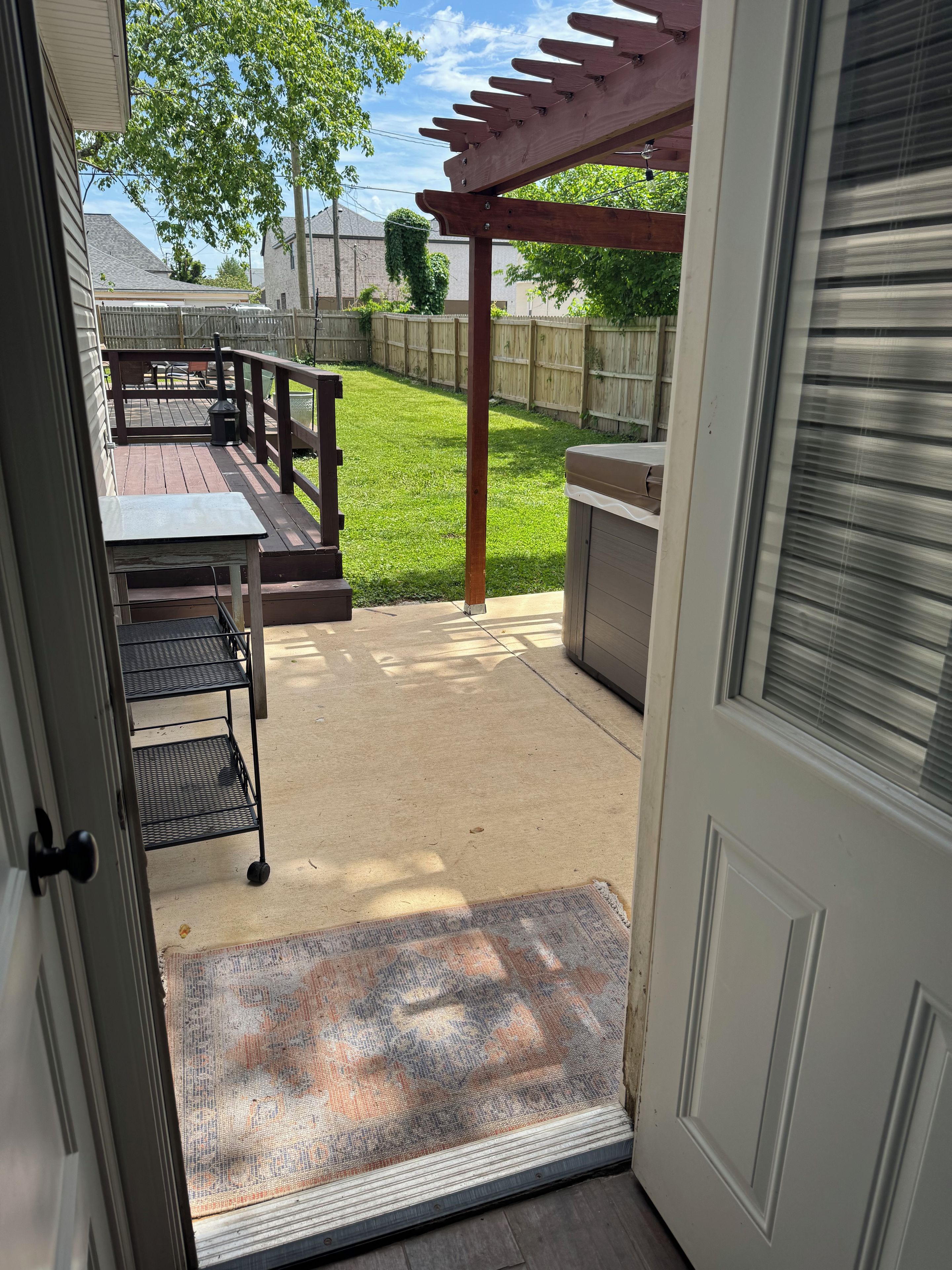 A patio with a pergola, a grill, and a covered table.