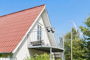Ein Haus mit rotem Ziegeldach, einem Balkon mit Metallgeländer und einem Schornstein.