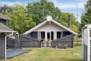 Een houten chalet met schuin dak, een schotelantenne en een schoorsteen.