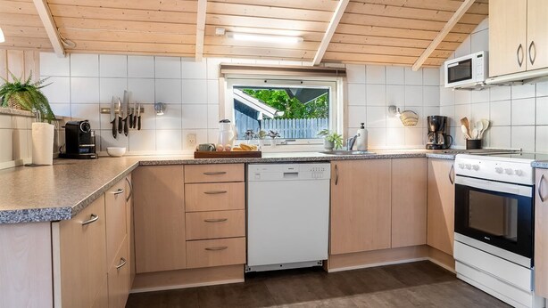 A modern kitchen with wooden cabinets, a Bosch dishwasher, a microwave, and a stove. - Holiday home by Limfjord, Storvorde (Storvorde)