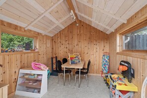 A wooden room with a table, chairs, a toy train set, and a window. - Holiday home by Limfjord, Storvorde (Storvorde)