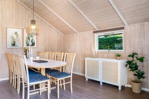A dining area with a round table, chairs, and a hanging light fixture.