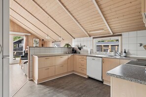 Une cuisine moderne avec des meubles en bois, un lave-vaisselle et une grande fenêtre.