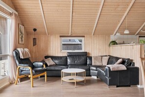 A cozy living room with a black leather sofa, a wooden chair, and a round coffee table.