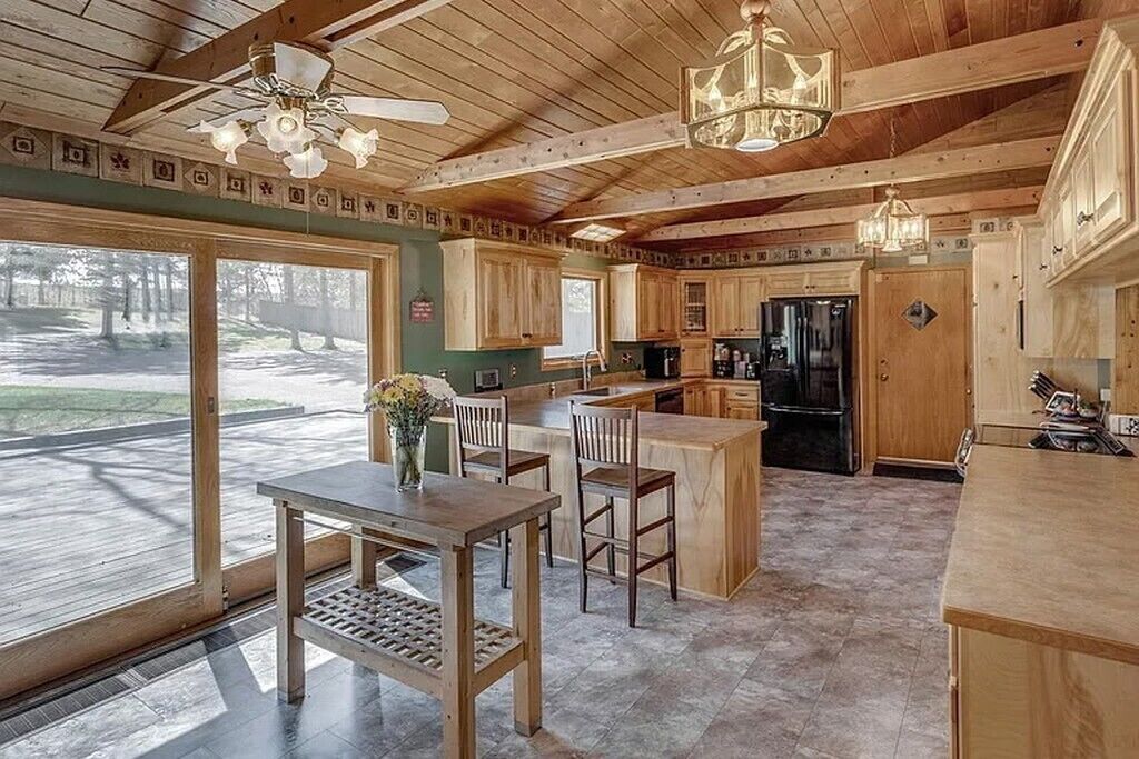 Une cuisine spacieuse avec des meubles en bois, un îlot central et un coin repas avec des chaises.